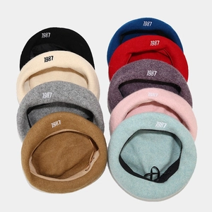 Detail view of colorful wool beret collection featuring white 1987 number embroidery