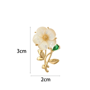 Elegant floral brooch with shell petals, golden metallic stem and green teardrop gem