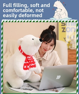 Soft white polar bear plush toy with red scarf held by a model in a cozy home setting