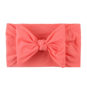 Detailed view of soft coral nylon headband featuring a large knitted decorative bow