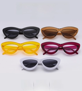 Détail de lunettes de soleil œil-de-chat empilées en noir, marron, jaune, rose et blanc
