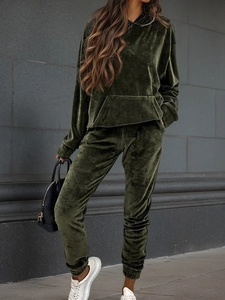 Detail of dark green velvet tracksuit showing plush texture on hoodie and joggers