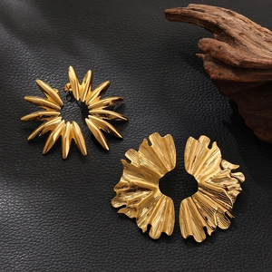 Irregular 18K gold petal and leaf earrings set on textured black background