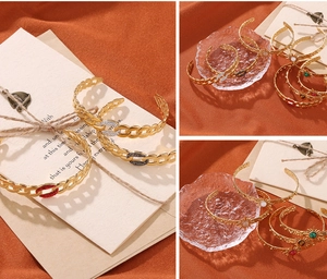 Detail of gold C-shaped cuff bracelets featuring zircon stones and sunburst charms