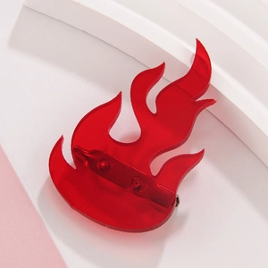 Detailed macro view of a translucent red acrylic flame brooch with metal pin backing
