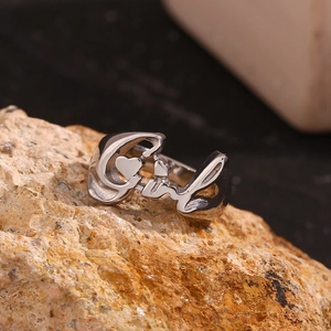 Macro shot of silver script 'Girl' ring with heart detail on orange textured rock