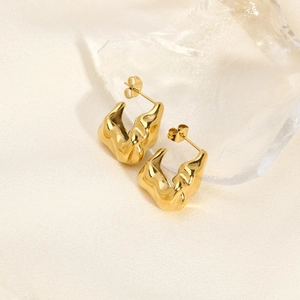 Detail of gold V-shaped earrings with irregular pleated texture on silk and ice background