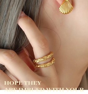 Close-up of golden shell earrings and double-layer lava textured ring on a model