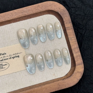 Silver cat eye press-on nails with star sequins and gradient finish on display tray