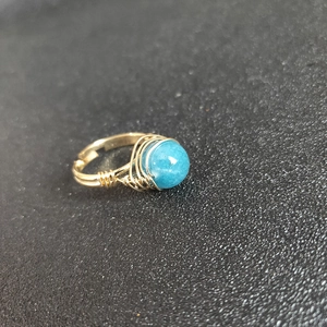 Detailed view of handmade gold wire-wrapped ring with a round blue natural stone