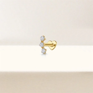 Macro detail of gold 925 silver stud earring featuring three diamonds and heart base