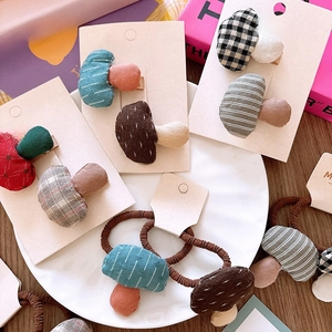 Detailed view of handmade checkered mushroom hair clips and elastics in ceramic bowl