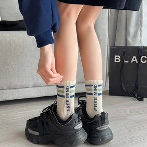 Détail de chaussettes en coton blanc avec rayures vertes et texte Free Mind