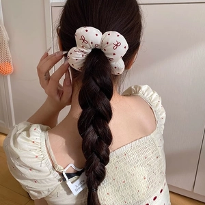 Floral print scrunchie with red bow patterns on white fabric shown on braided hair