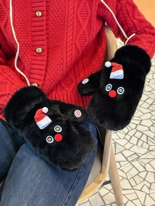 Detail of plush black snowman mittens featuring a cute red mini hat and soft faux fur texture
