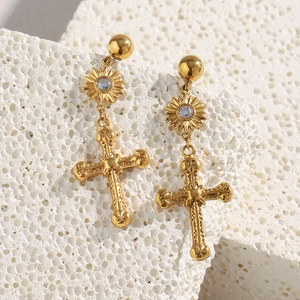 Détail de boucles d'oreilles croix en acier plaqué or 18K avec motif solaire et pierre