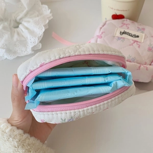 Quilted white square cosmetic bag with pink zipper holding sanitary pads for storage