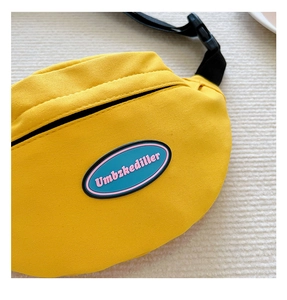 Detailed close-up of yellow canvas kids belt bag with blue lettered brand patch