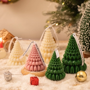 Close-up of tree-shaped scented candles in festive snow scene with holiday decor