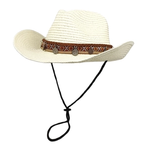 Detail of straw cowboy hat with ethnic patterned band and antique metal coin charms