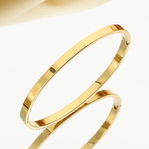 Close-up of a polished gold oval bangle showing its high-gloss finish and sleek surface