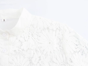 Close-up of white lace blouse featuring delicate floral patterns and stand collar detail
