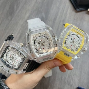 Three tonneau-shaped watches with transparent cases and skeletal movements in white, black, and yellow