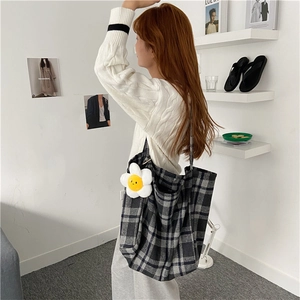 Lifestyle detail of a large plaid wool tote bag being worn by a model in a room