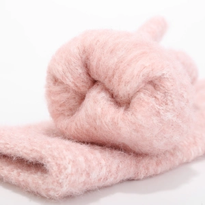 Close-up of thick pink knitted fabric showing soft fuzzy texture and warm thermal material