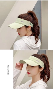 Detail view of light green open top sun visor with purple sports embroidery for women