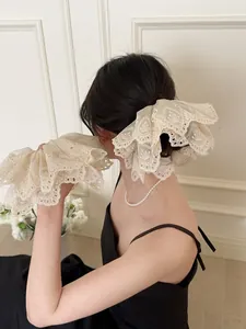 Detailed view of beige lace embroidered scrunchie worn on a French style ponytail