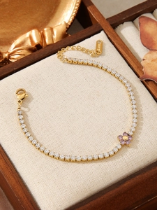 Detail of gold stainless steel tennis bracelet with white zircon and purple flower charm