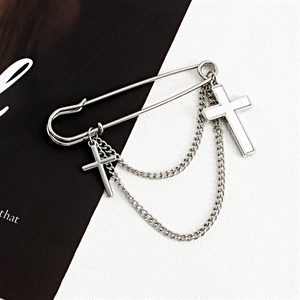 Detail of silver cross brooch featuring white shell inlay and elegant hanging chains
