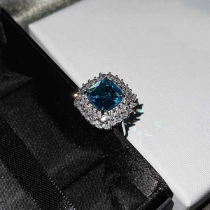 Macro shot of silver ring featuring square blue topaz surrounded by white stones
