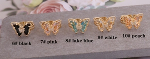 Detail view of colorful 3D crystal butterfly rings on grey stone with model codes
