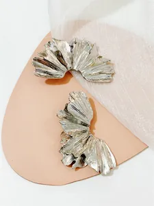 Detail of silver twist hoop earrings with hammered texture on soft pink backdrop
