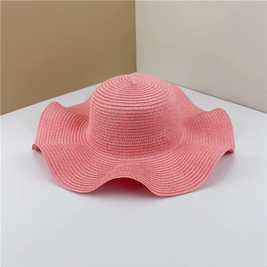 Detail of pink wide brim straw sun hat featuring decorative wavy edges and woven texture