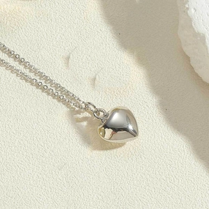 Close-up of heart pendant necklace with polished silver finish on a stone texture