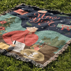 Detail of woven Christmas tree blanket with New Year illustration and tassel fringe outdoors