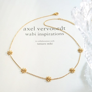 Elegant gold plated titanium daisy flower necklace displayed on a vintage book