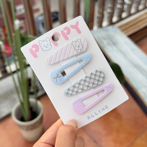 Detailed view of four colorful candy-colored hair clips held in hand against greenery