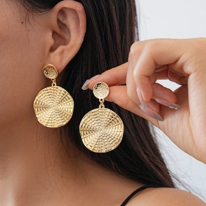 Detailed view of gold geometric woven texture hoop earrings worn by a female model