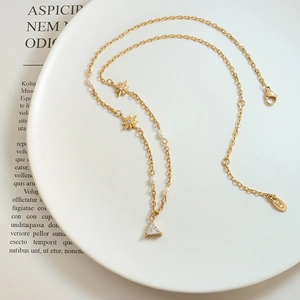 Elegant 18K gold star and pearl necklace with a triangular zircon pendant in white ceramic tray