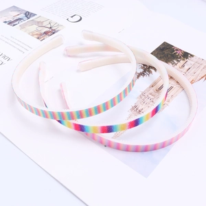 Detail showing non-slip teeth inside colorful rainbow striped kids headbands on a book