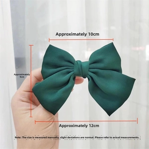 Detail view of large forest green satin bow hair clip with 12cm width and glossy texture