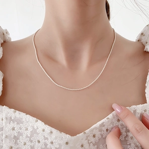 Close-up of minimalist silver pearl necklace on model with white lace outfit
