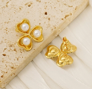 Detail of gold flower stud earrings with three pearls on a silk and stone background