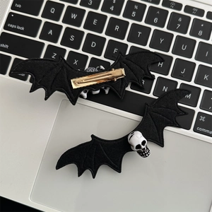 Gothic bat wing hair clips with resin skull decor on silver laptop keyboard background