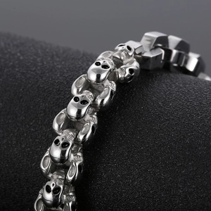 Macro detail showing vintage punk style silver skull links on a men's stainless steel bracelet