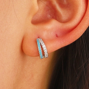 Detail of silver huggie earrings with blue turquoise and white cubic zirconia stones